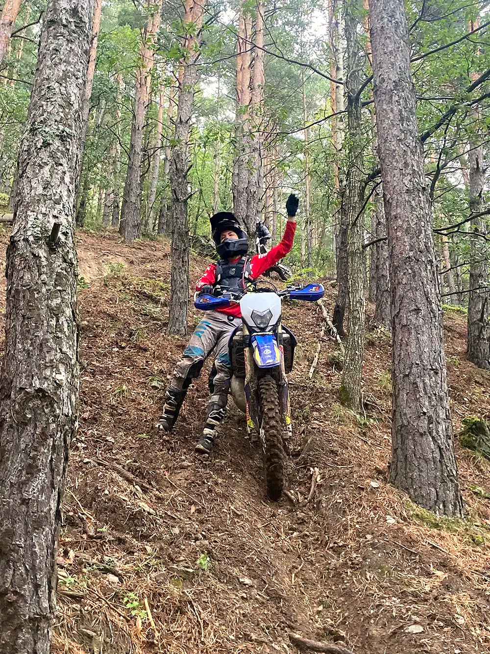 Rider raising a fist halfway up a rutted forest climb