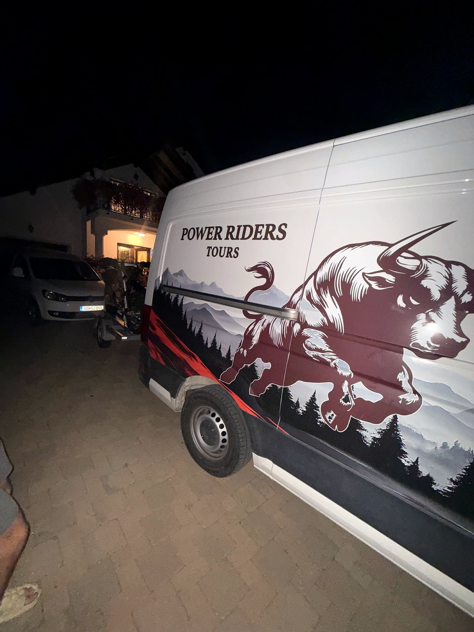 Power Riders Tours support van with the charging bull, parked at the guesthouse at night